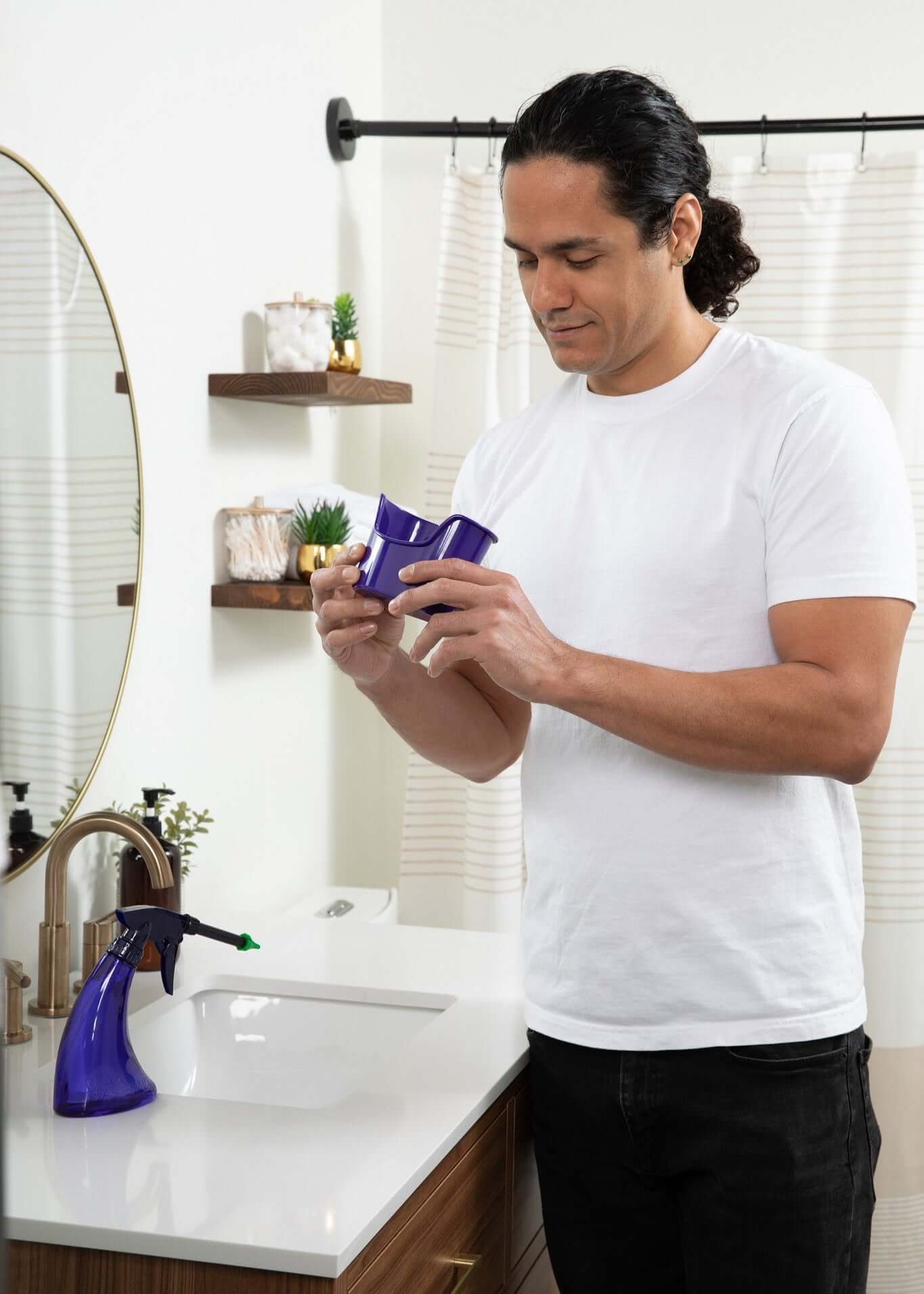 Man cleaning a bathroom with a spray bottle in hand, demonstrating effective cleaning techniques.