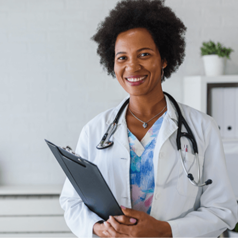 Smiling female doctor in a white coat holding a clipboard in a modern clinic setting. eosera EAR WAX MD is proven to work better than the leading competitor DEBROX