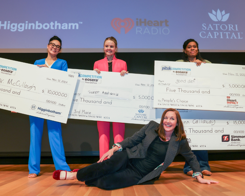 People holding large check awards on a stage.