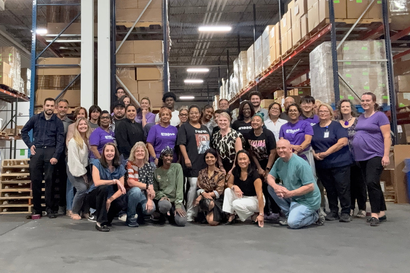 Group of people posing for a photo in a warehouse setting